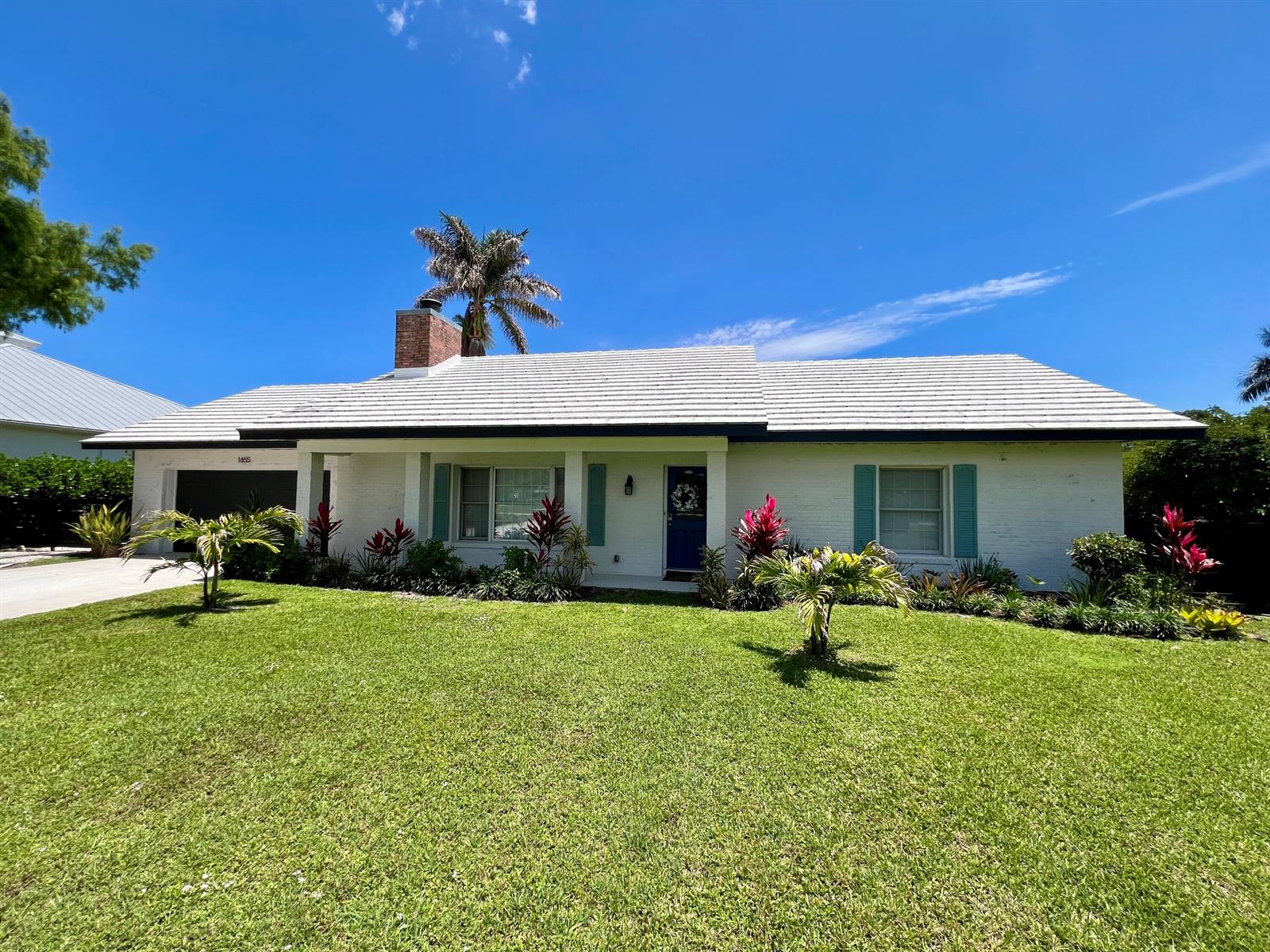 A white, single-story ranch-style house with a blue door and a green lawn — 1655 NW Fork Road, Stuart FL 34994, STUART, FL