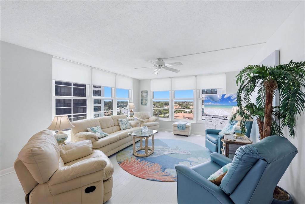 A living room features cream leather sofas, a blue armchair, and a circular area rug — 629 ALHAMBRA ROAD UNIT 702, VENICE, FL