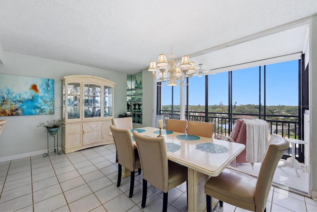 A dining room features a table with six chairs, a china cabinet, and a balcony view — 629 ALHAMBRA ROAD UNIT 702, VENICE, FL