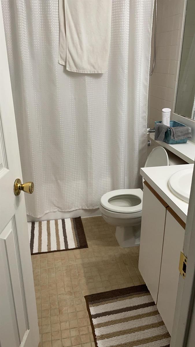 A small bathroom features a white toilet, a shower with a curtain, and a vanity — 17485 NW 67th Court # 21, Hialeah FL 33015, HIALEAH, FL