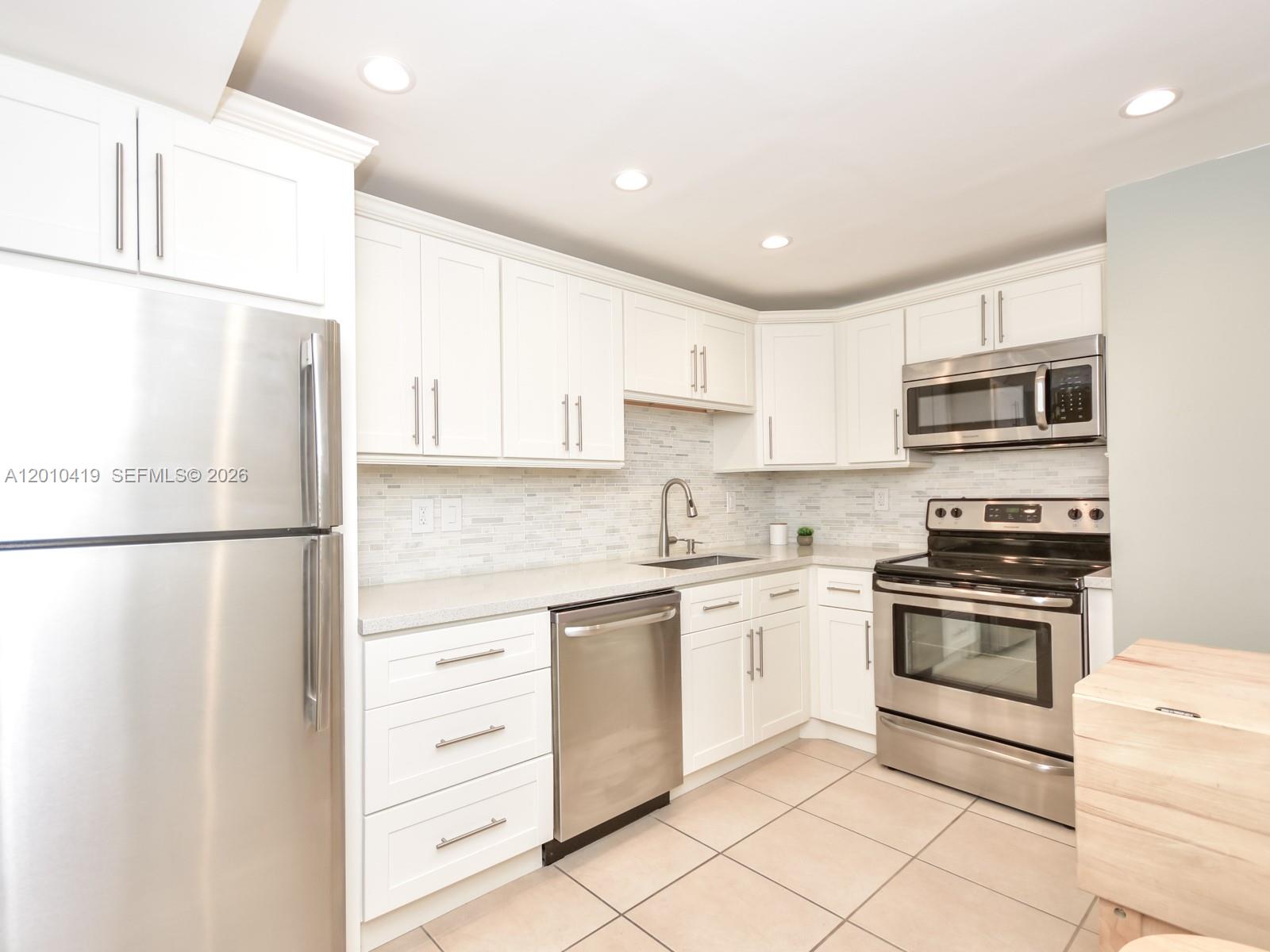 A kitchen features white cabinets, stainless steel appliances, and a light-colored tiled floor — 780 NE 69th St # 1908, Miami FL 33138, MIAMI, FL