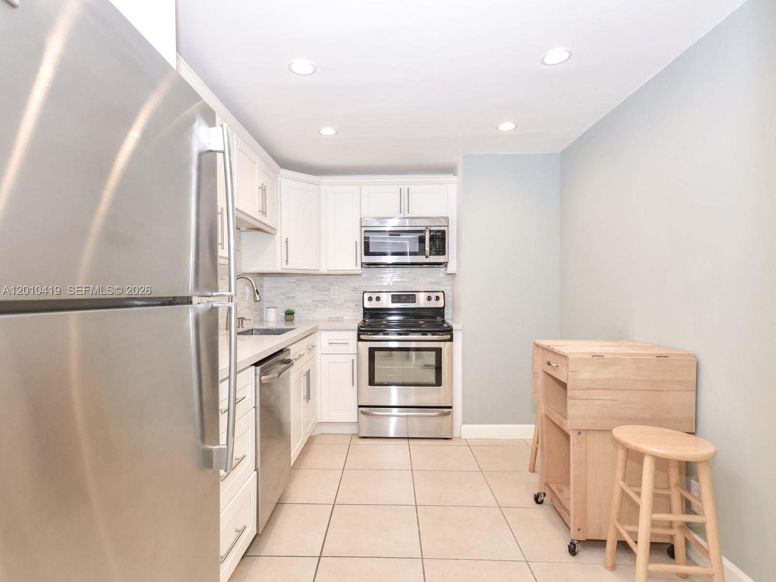 A kitchen features white cabinets, stainless steel appliances, and a light-colored tile floor — 780 NE 69th St # 1908, Miami FL 33138, MIAMI, FL