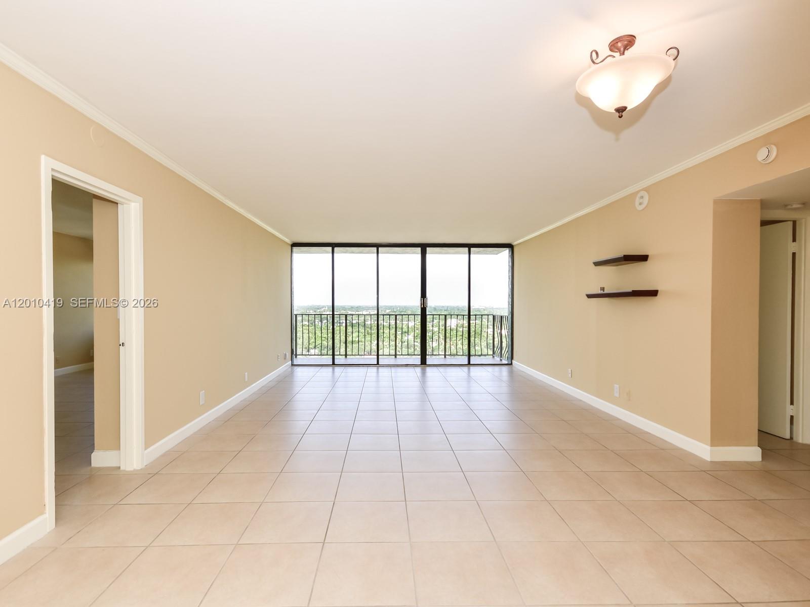An empty room with beige walls, tile flooring, and a sliding glass door to a balcony — 780 NE 69th St # 1908, Miami FL 33138, MIAMI, FL