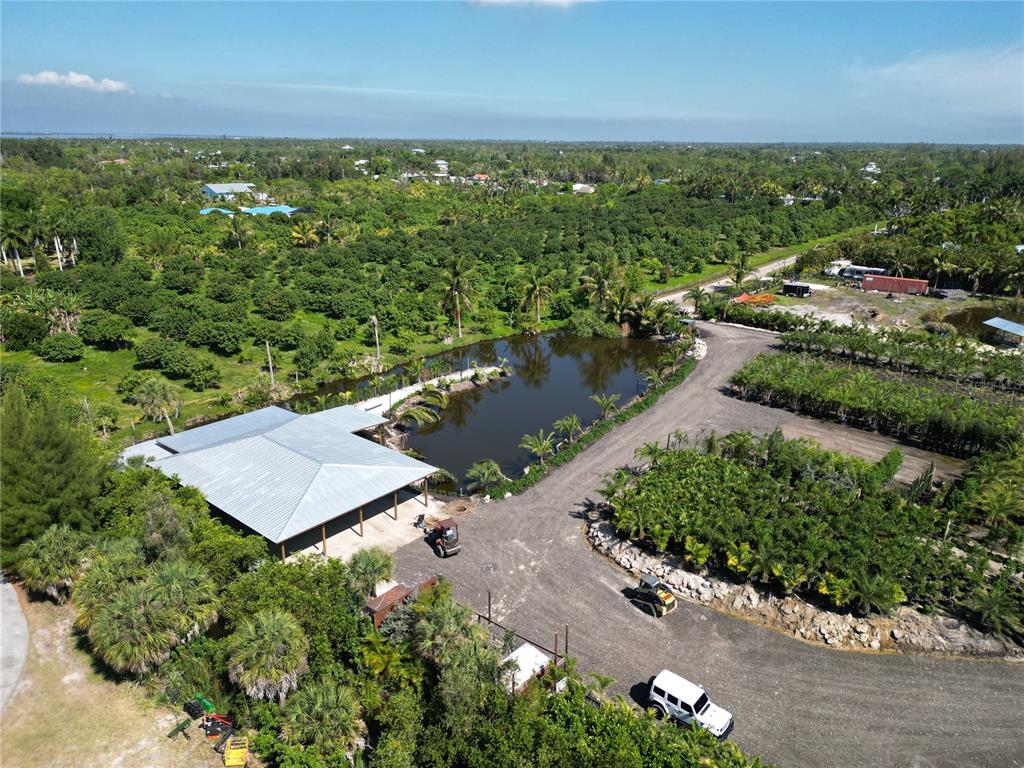 An aerial view shows a metal-roofed building, a pond, and a nursery on a property — 12242 EAGLES NEST DRIVE, BOKEELIA, FL