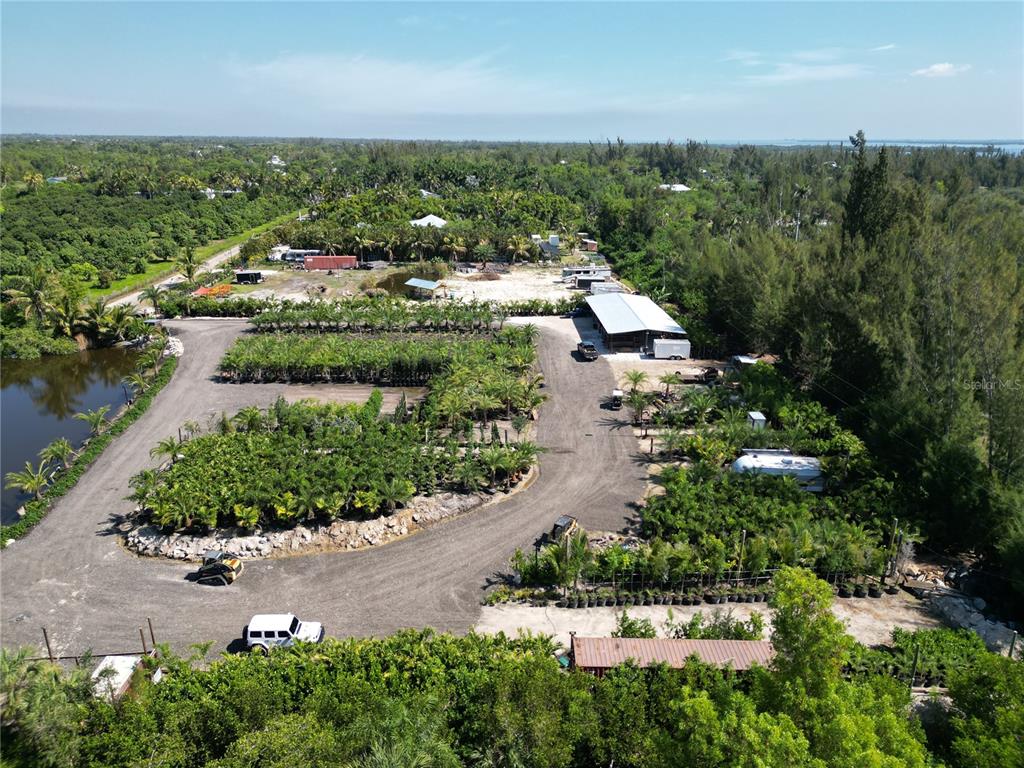 An aerial view shows a plant nursery with rows of potted palms and a metal building — 12242 EAGLES NEST DRIVE, BOKEELIA, FL