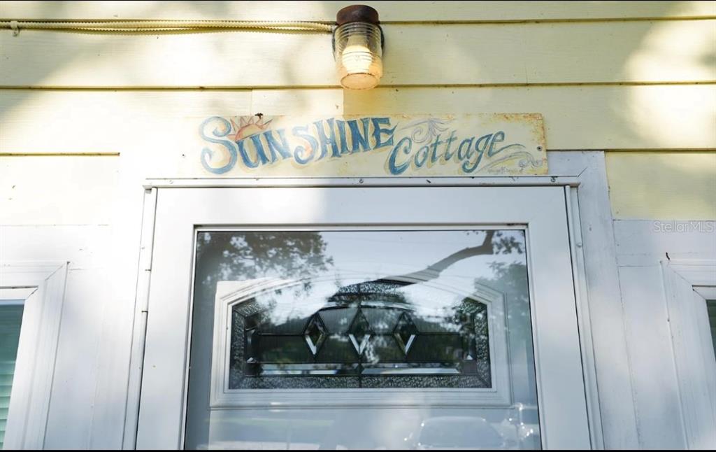 A yellow exterior wall features a sign reading Sunshine Cottage above a white front door — 526 5TH AVENUE N, SAFETY HARBOR, FL