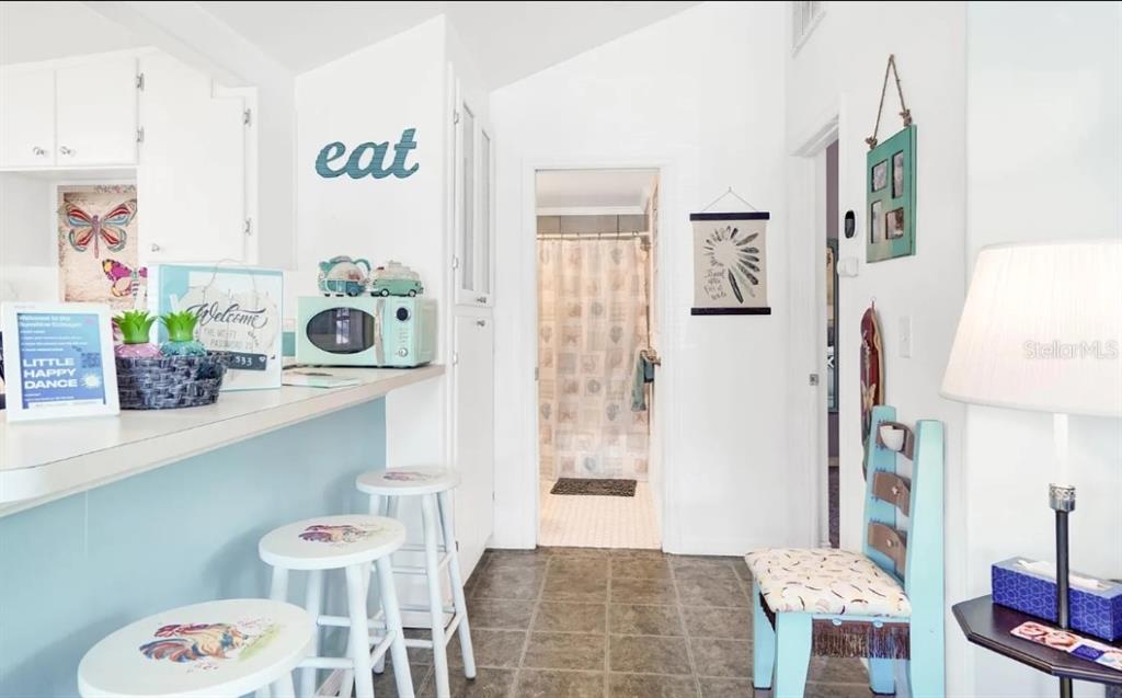 A kitchen with a breakfast bar, stools, and a doorway leading to a bathroom — 526 5TH AVENUE N, SAFETY HARBOR, FL