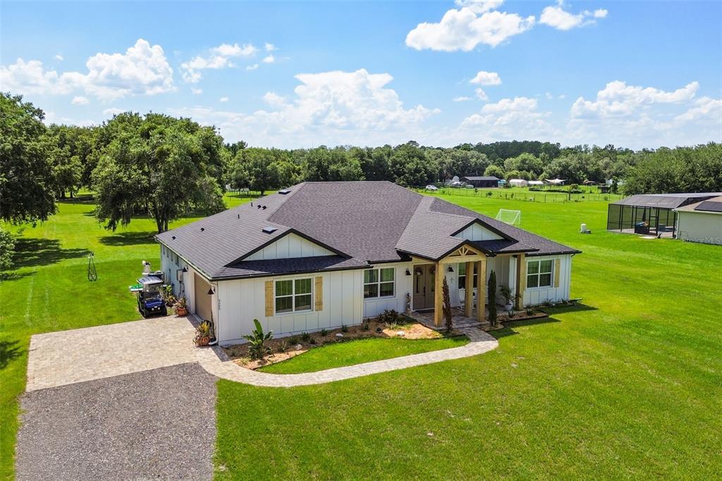 An aerial view of a white farmhouse-style home with a dark roof and large lawn — 4280 TUCKER AVENUE, ST CLOUD, FL