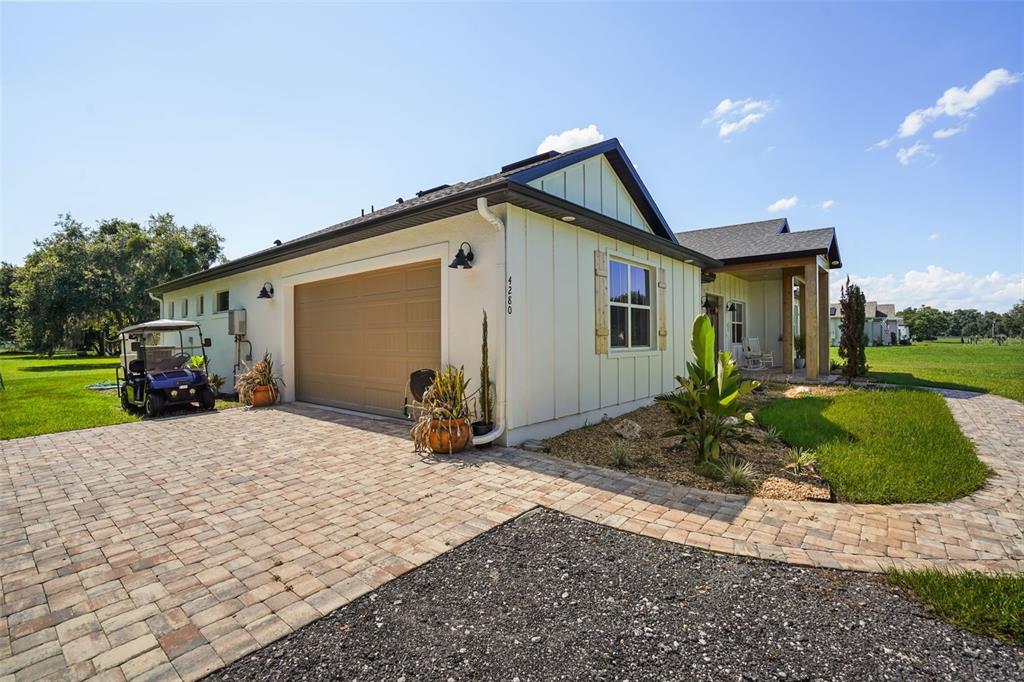 A modern farmhouse-style home features a paved driveway, a two-car garage, and a golf cart — 4280 TUCKER AVENUE, ST CLOUD, FL