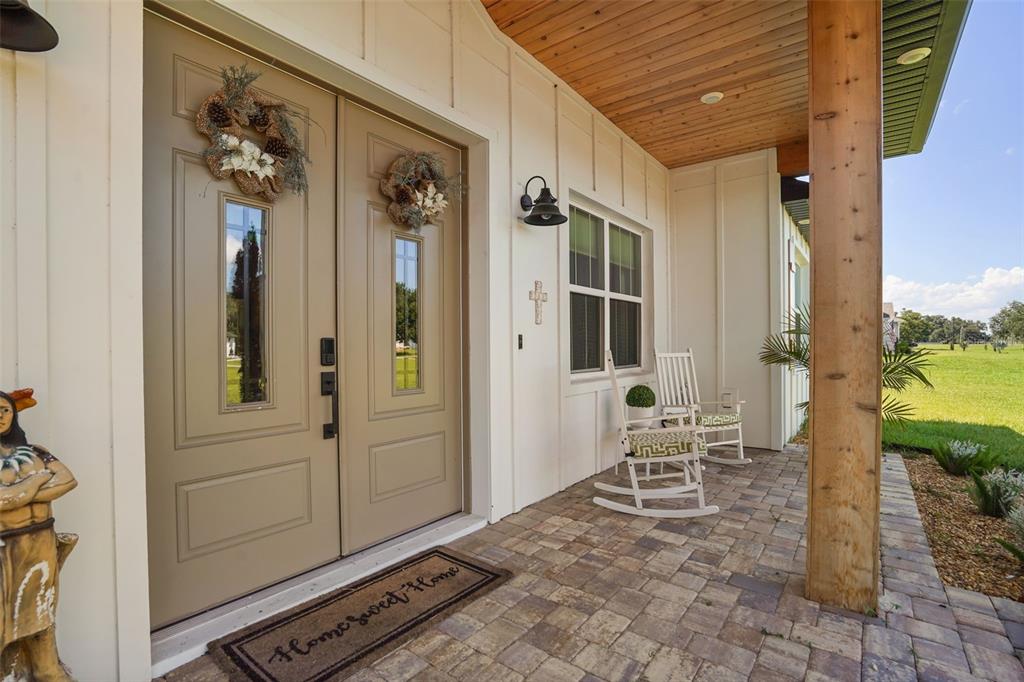A covered front porch features double doors, a paver floor, and two white rocking chairs — 4280 TUCKER AVENUE, ST CLOUD, FL