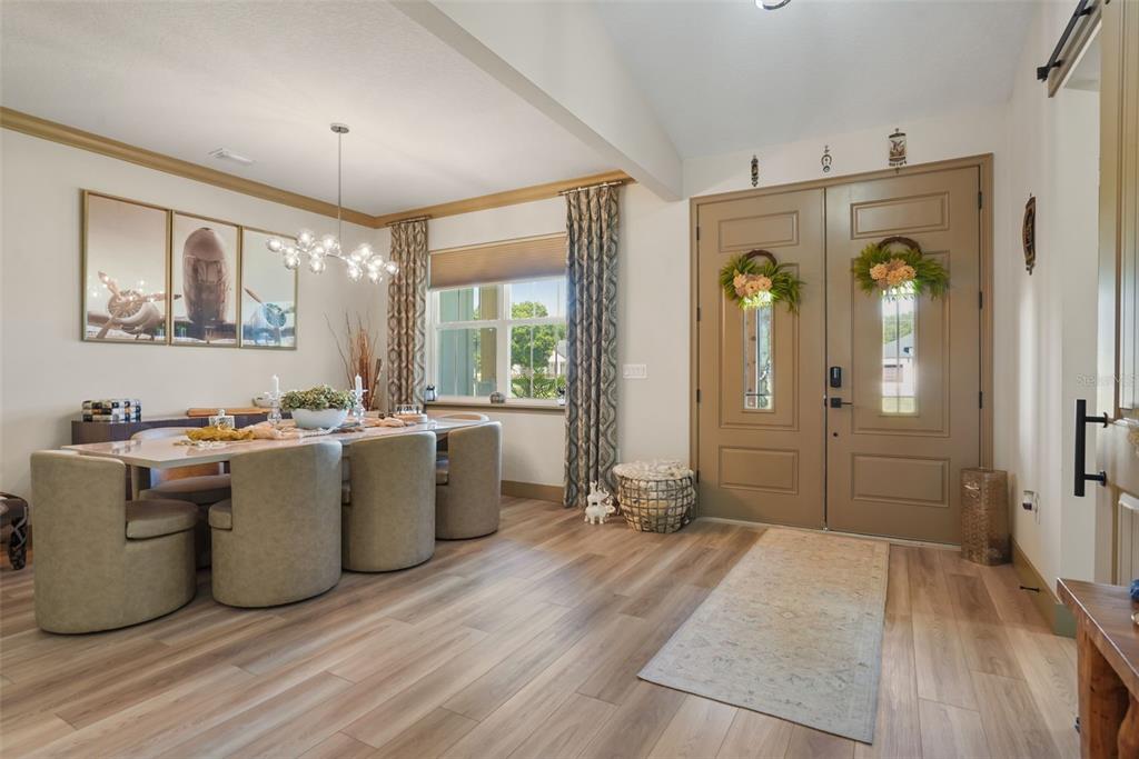 A dining area with a long table and chairs sits beside a double-door entryway — 4280 TUCKER AVENUE, ST CLOUD, FL
