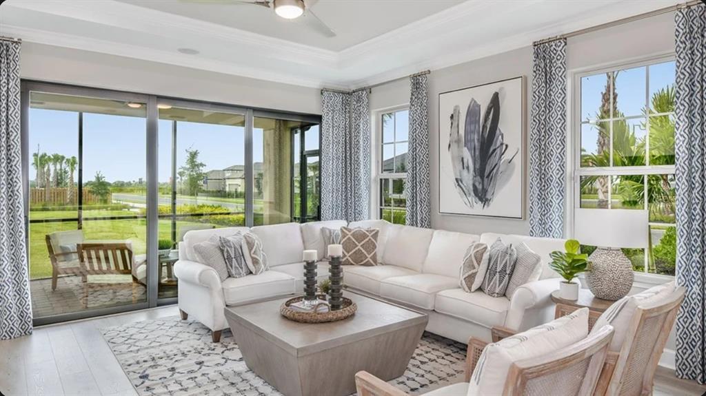 A bright living room features a white sectional sofa, a square coffee table, and large windows — 7532 MOONBEAM AVENUE, SARASOTA, FL
