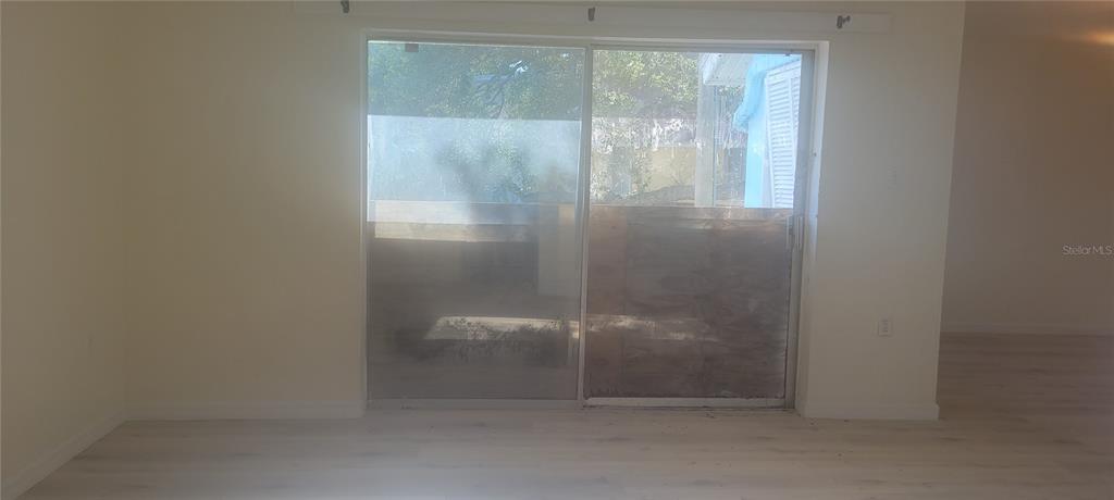 A room with light-colored flooring and a sliding glass door leading to an outdoor area — 3775 40TH LANE S UNIT L, ST PETERSBURG, FL