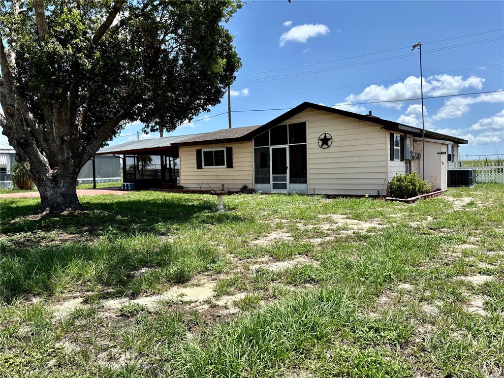 A single-story house with light-colored siding, a screened porch, and a large tree in front — 2302 MARTHA DRIVE, LAKE ALFRED, FL