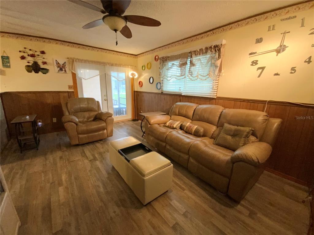 A living room features wood-paneled walls, a leather sofa and chair, and a wall clock — 2302 MARTHA DRIVE, LAKE ALFRED, FL