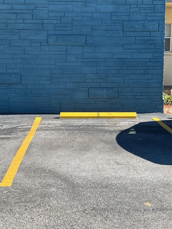 A parking space marked with the number three sits in front of a blue wall — 5750 80TH STREET N UNIT B203, ST PETERSBURG, FL