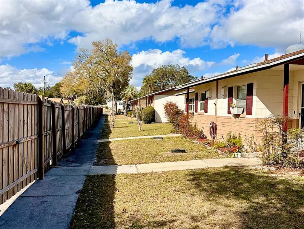 A side view of a single-story building with a wooden fence and a concrete walkway — 712 E ARIZONA AVENUE UNIT A, DELAND, FL