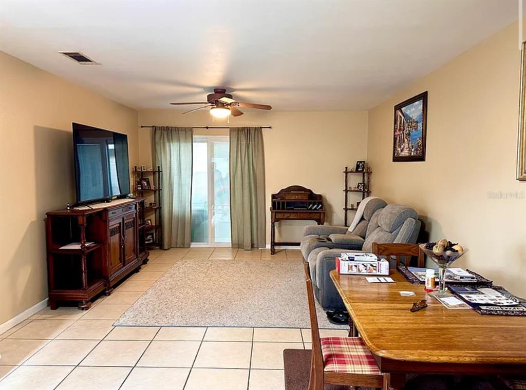 A living room with tile floors, a ceiling fan, a television, and a dining area — 712 E ARIZONA AVENUE UNIT A, DELAND, FL