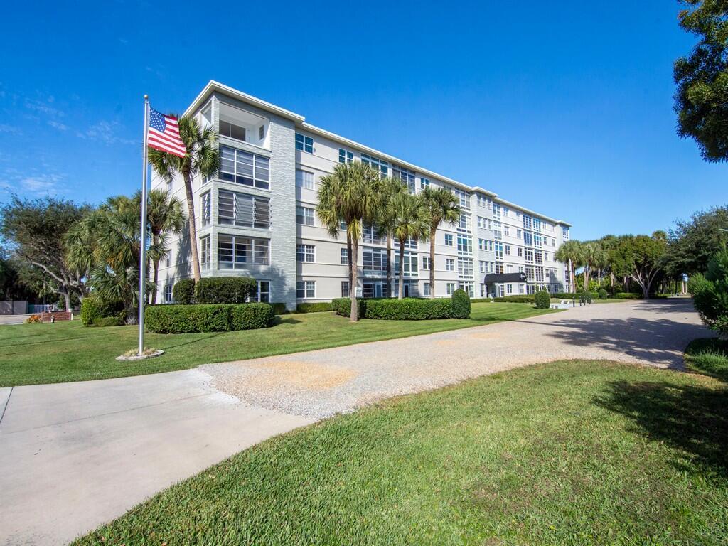 A four-story apartment building with a light-colored facade stands beside a lawn and driveway — 2333 Indian River Boulevard # 506, Vero Beach FL 32960, VERO BEACH, FL