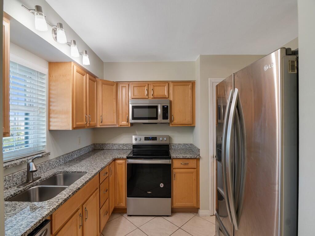 A kitchen featuring light wood cabinets, granite countertops, stainless steel appliances, and tile flooring — 2333 Indian River Boulevard # 506, Vero Beach FL 32960, VERO BEACH, FL