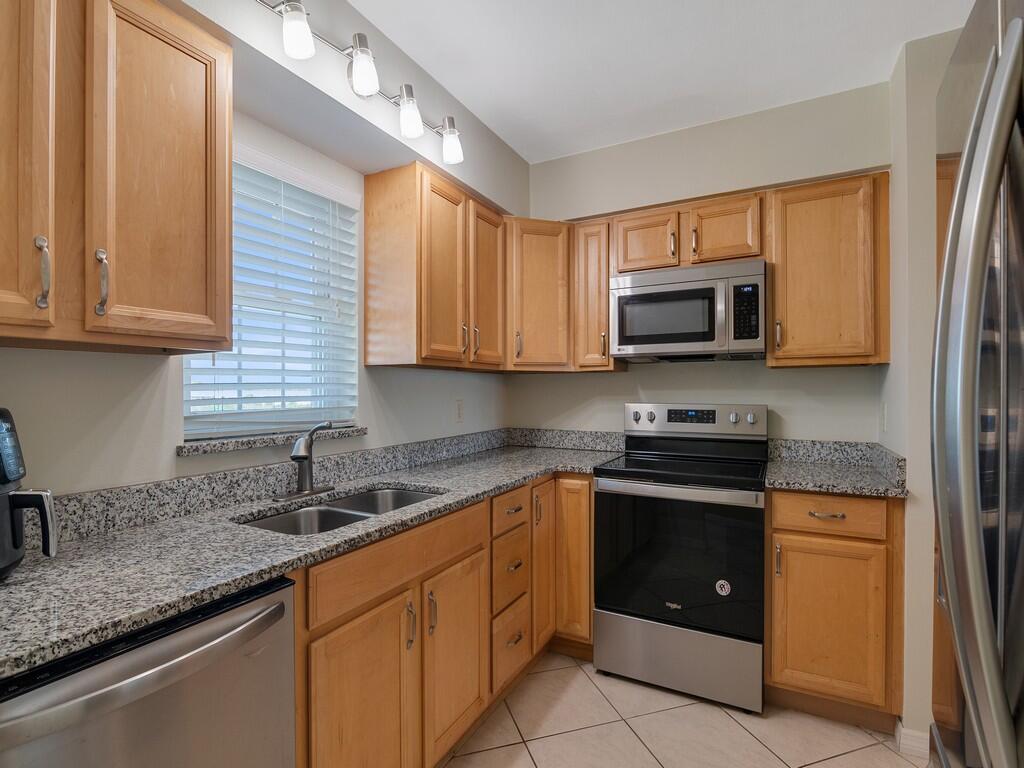 A kitchen with light wood cabinets, granite countertops, and stainless steel appliances — 2333 Indian River Boulevard # 506, Vero Beach FL 32960, VERO BEACH, FL
