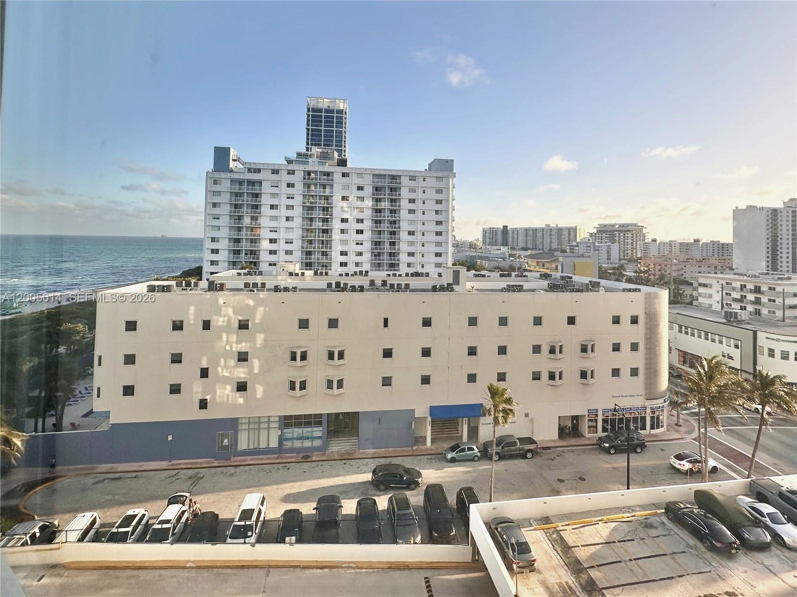 An exterior view shows a multi-story building with a parking lot and ocean in the background — 7135 COLLINS AVE # 811, Miami Beach FL 33141, MIAMI BEACH, FL
