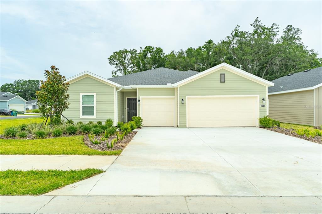 A single-story house with light green siding, a two-car garage, and a concrete driveway — 6913 SW 87TH STREET, OCALA, FL