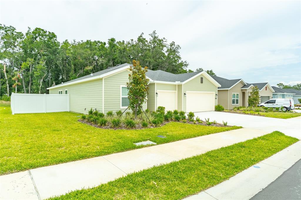 A light green single-story house with a two-car garage and a white privacy fence — 6913 SW 87TH STREET, OCALA, FL