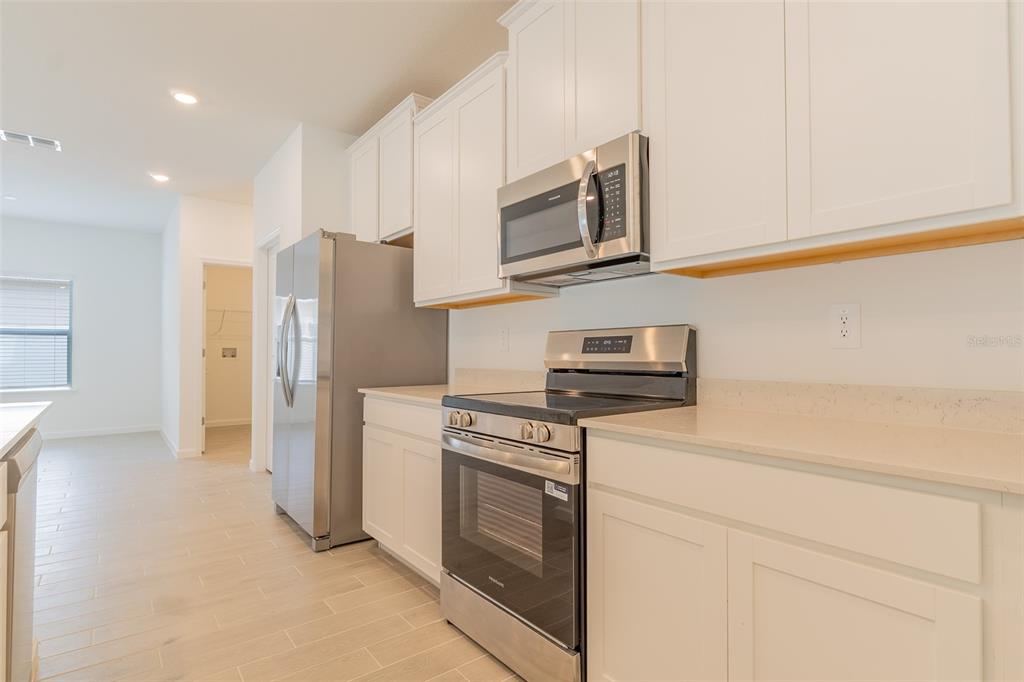 A kitchen features white cabinets, stainless steel appliances, and light-colored countertops — 6913 SW 87TH STREET, OCALA, FL