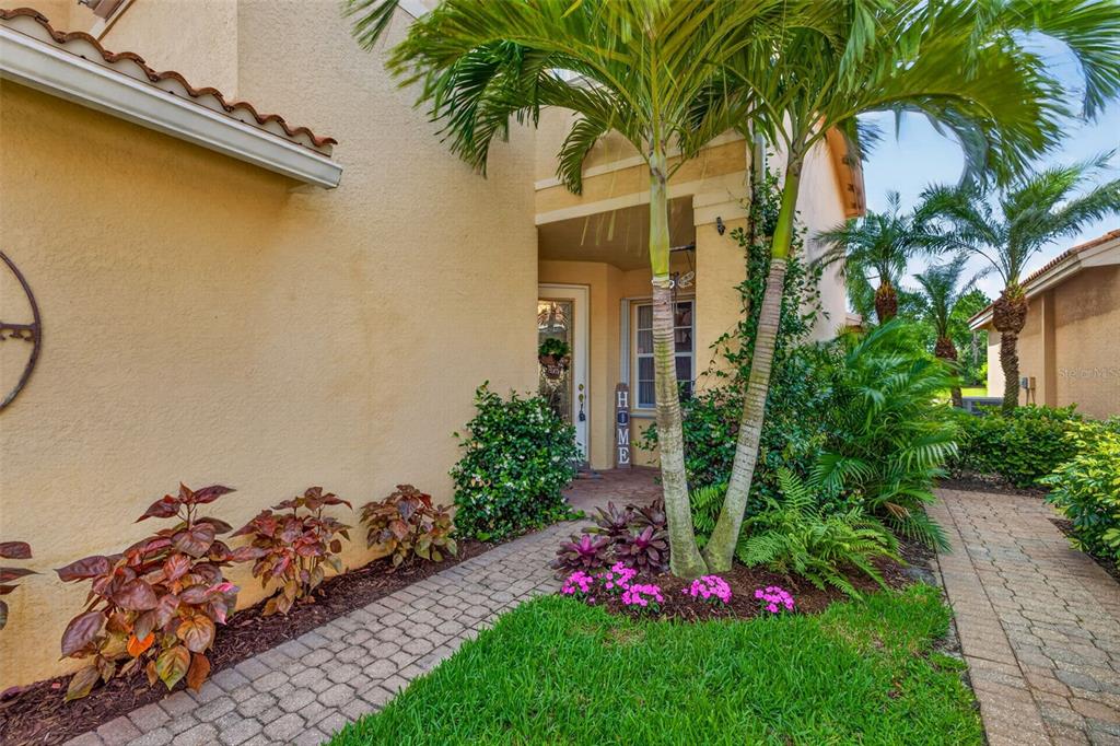 A paved walkway leads to the front entrance of a house with palm trees — 10284 CREPE JASMINE LANE, FORT MYERS, FL