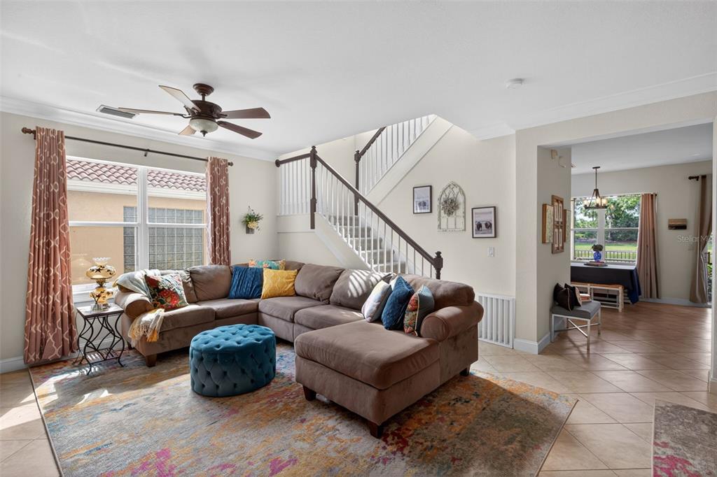 A living room features a brown sectional sofa, a blue ottoman, and a staircase — 10284 CREPE JASMINE LANE, FORT MYERS, FL