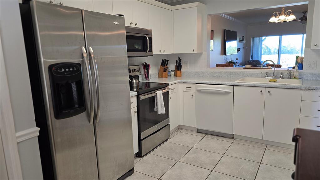 A kitchen features white cabinets, stainless steel appliances, a white dishwasher, and light tile flooring — 2725 TERRA CEIA BAY BOULEVARD UNIT 102, PALMETTO, FL