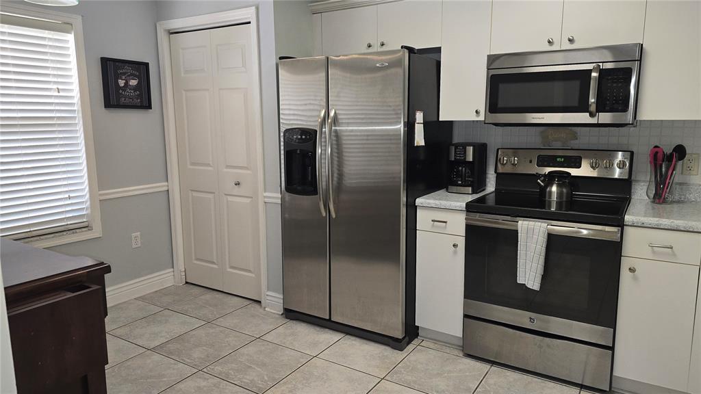 A kitchen features stainless steel appliances, white cabinets, and light-colored tile flooring — 2725 TERRA CEIA BAY BOULEVARD UNIT 102, PALMETTO, FL