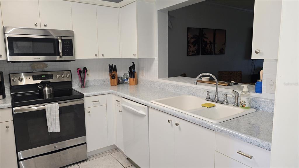 A kitchen features white cabinets, stainless steel appliances, a double sink, and light-colored countertops — 2725 TERRA CEIA BAY BOULEVARD UNIT 102, PALMETTO, FL