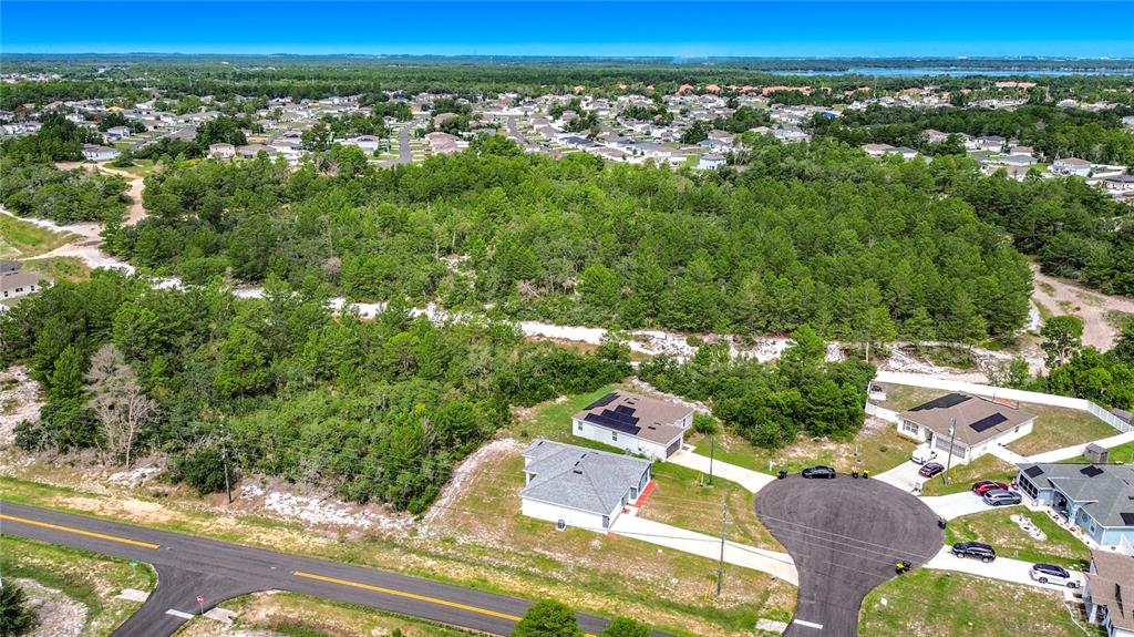 An aerial view shows a suburban neighborhood with houses, a cul-de-sac, and wooded land — 106 OAK CIRCLE, POINCIANA, FL