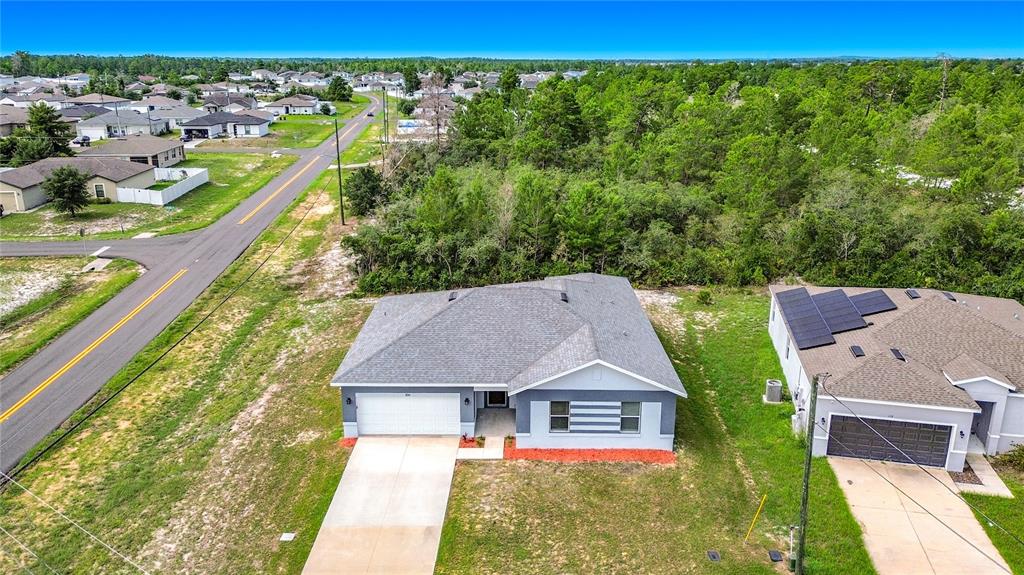 An aerial view shows a single-story house with a gray roof and a concrete driveway — 106 OAK CIRCLE, POINCIANA, FL