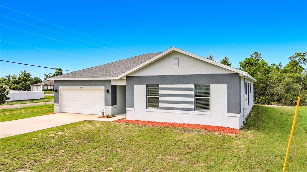 A single-story house with a white and gray exterior, a garage, and a lawn — 106 OAK CIRCLE, POINCIANA, FL