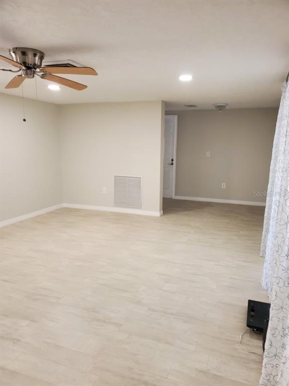 A room with light-colored tile flooring, a ceiling fan, and a doorway leading to another area — 8504 WAGON WHEEL LANE, HUDSON, FL