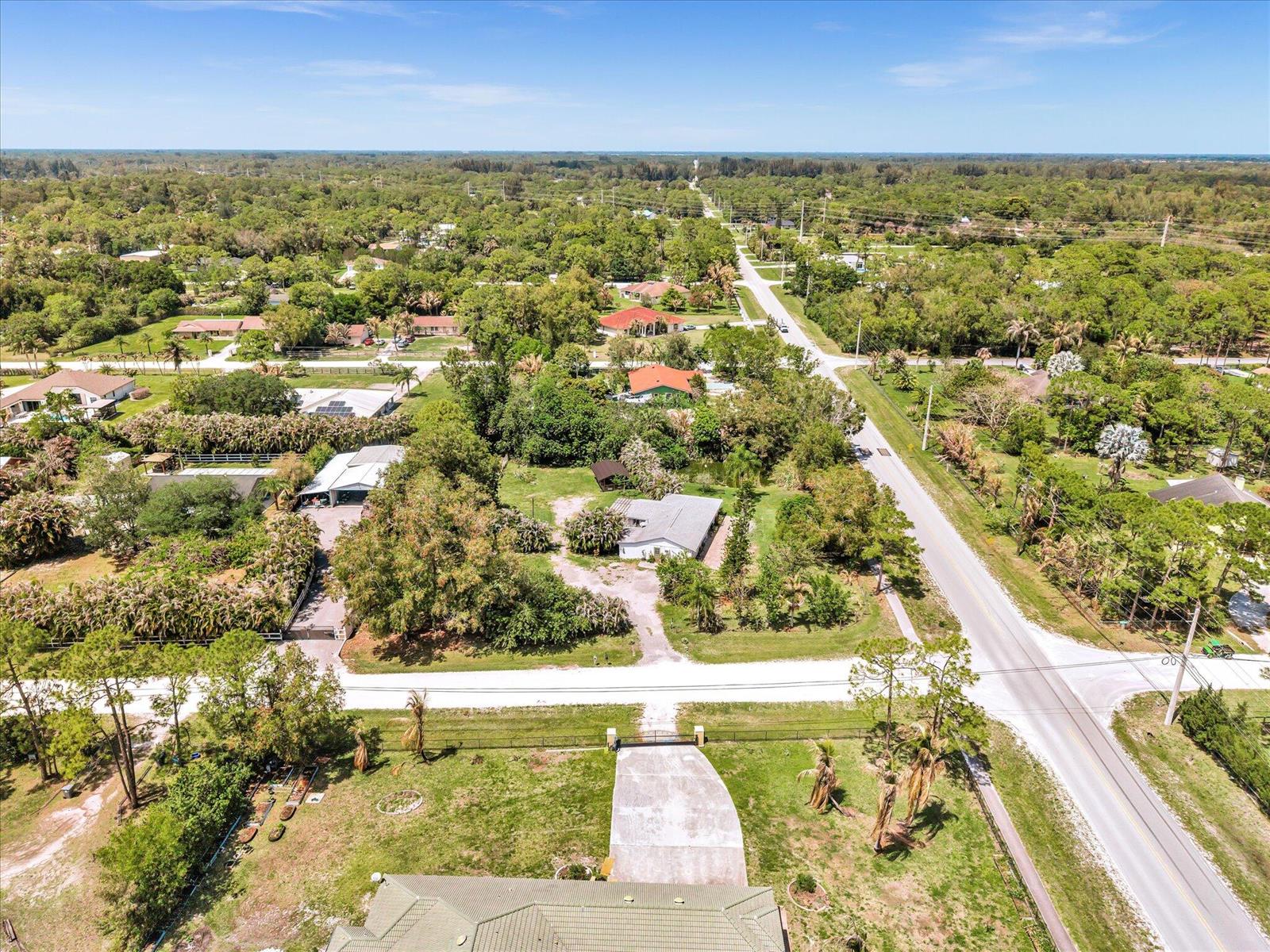 An aerial view shows a residential property with a driveway, trees, and surrounding neighborhood roads — 5209 Coconut Boulevard, FL 33411, FL