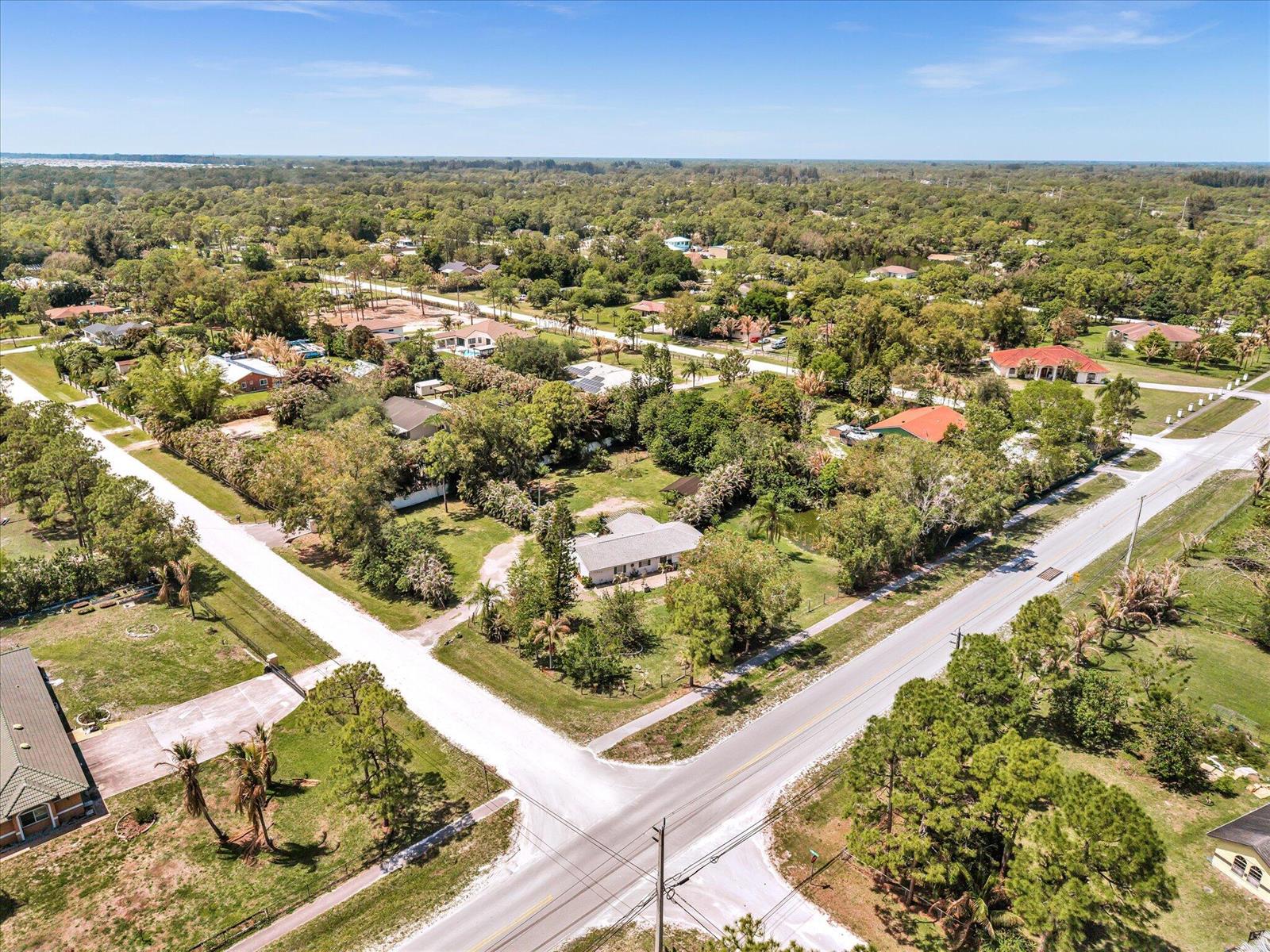 An aerial view shows a single-story house surrounded by trees near a paved road intersection — 5209 Coconut Boulevard, FL 33411, FL