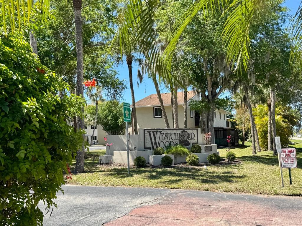 The entrance sign for Westchester Woods stands in front of a multi-story apartment building — 22481 WESTCHESTER BOULEVARD UNIT B36, PORT CHARLOTTE, FL