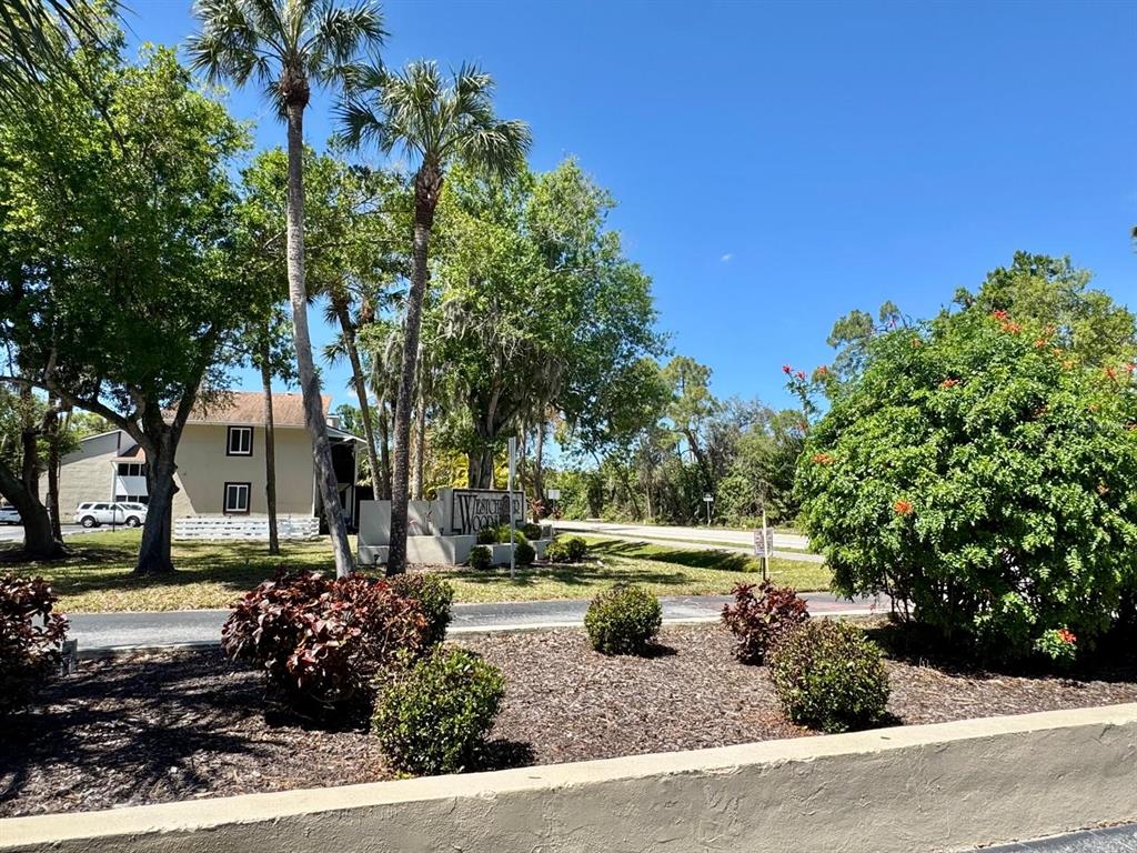 A sign for Westchester Woods stands near palm trees and a multi-story residential building — 22481 WESTCHESTER BOULEVARD UNIT B36, PORT CHARLOTTE, FL