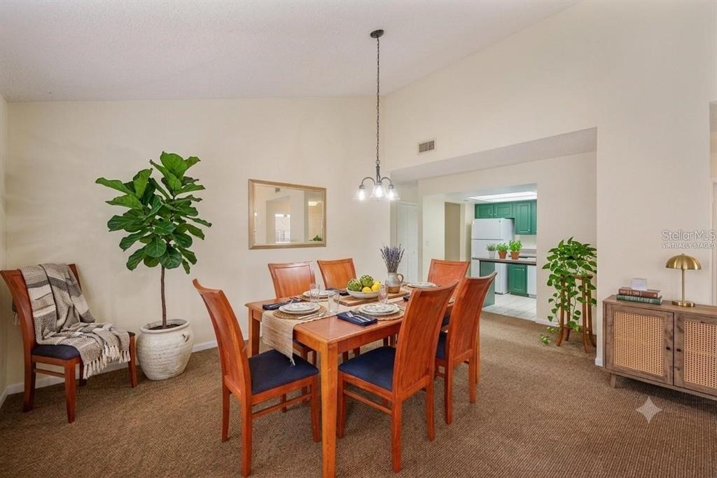 A dining room features a wooden table with six chairs, a hanging light, and carpet — 4231 OAK LOOP UNIT 51, MULBERRY, FL