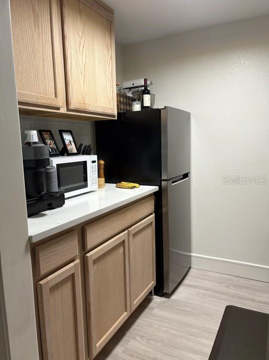 A living room features a black leather sectional, glass coffee table, and sliding glass patio doors — 36750 US HIGHWAY 19 N UNIT 6-105, PALM HARBOR, FL