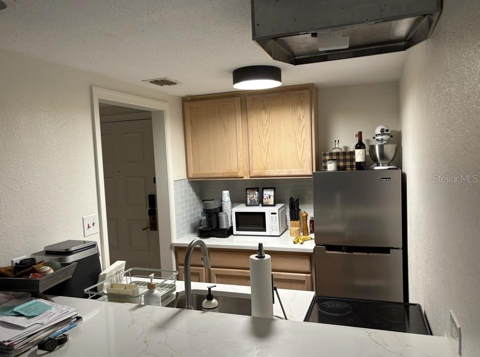 A living room features a grey sectional sofa, glass coffee table, and a kitchen breakfast bar — 36750 US HIGHWAY 19 N UNIT 6-105, PALM HARBOR, FL