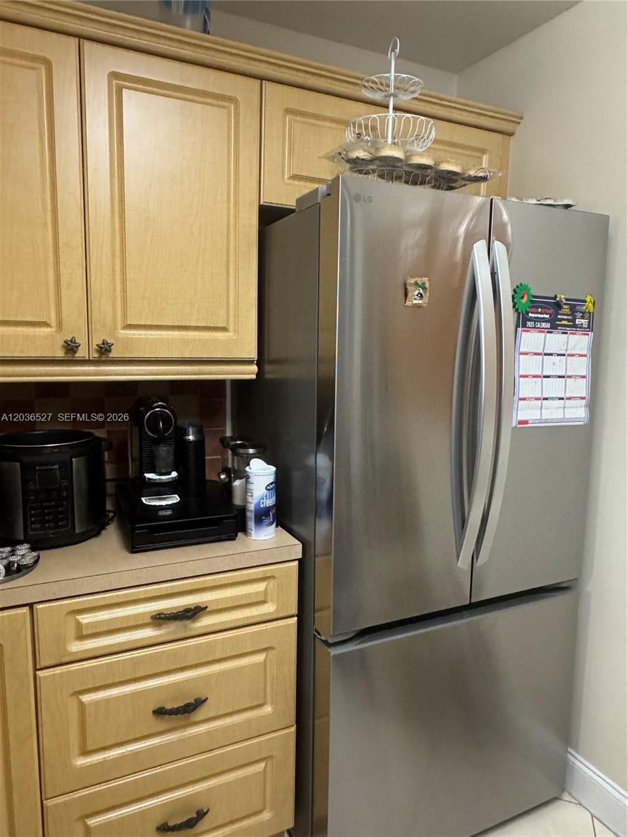 A stainless steel refrigerator stands next to wooden cabinets and a countertop with appliances — 8625 NW 8th St # 310, Miami FL 33126, MIAMI, FL