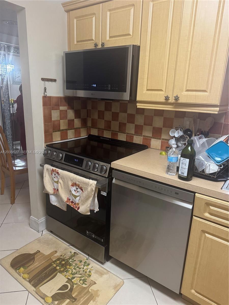 A kitchen features light wood cabinets, stainless steel appliances, and a checkered tile backsplash — 8625 NW 8th St # 310, Miami FL 33126, MIAMI, FL