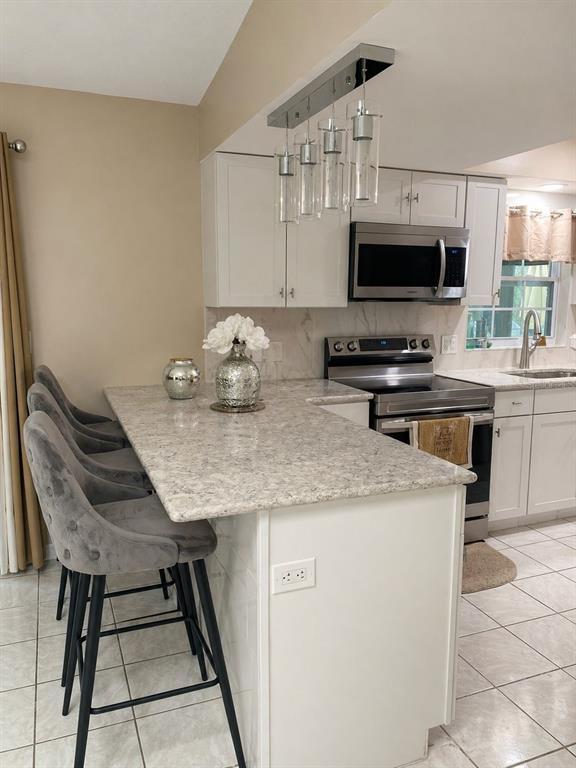 A kitchen features white cabinets, granite countertops, a stainless steel stove, and three gray stools — 4805 SPARROW DRIVE, ST CLOUD, FL