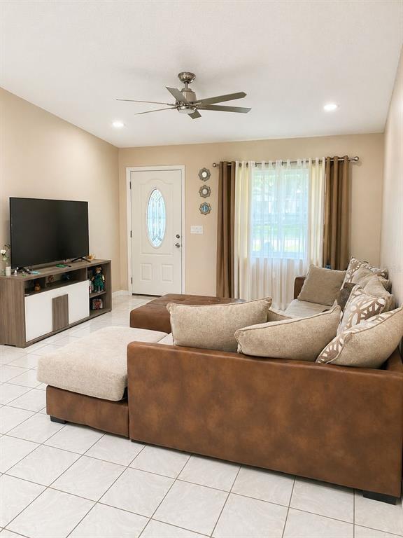 A living room features a brown sectional sofa, a television console, and a ceiling fan — 4805 SPARROW DRIVE, ST CLOUD, FL