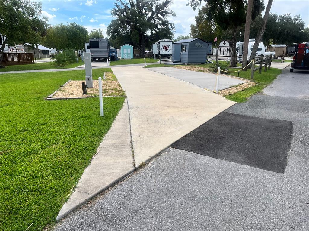 A concrete RV pad features a utility hookup post and a small adjacent storage shed — 2888 NE 102ND TERRACE, SILVER SPRINGS, FL
